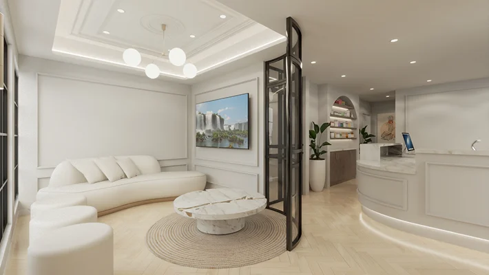 Elegant lobby with a curved white sofa, marble coffee table, and a reception desk under bright lighting.